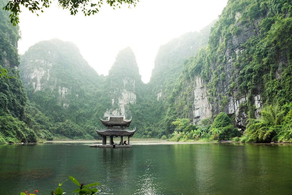 pagoda circondata da specchio d'acqua e montagne in Vietnam